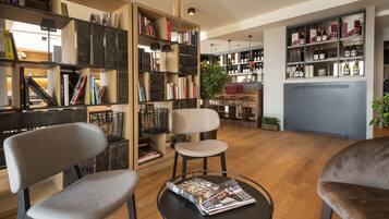 A modern interior with wooden bookshelves, a round table with magazines, and a seating area with chairs.
