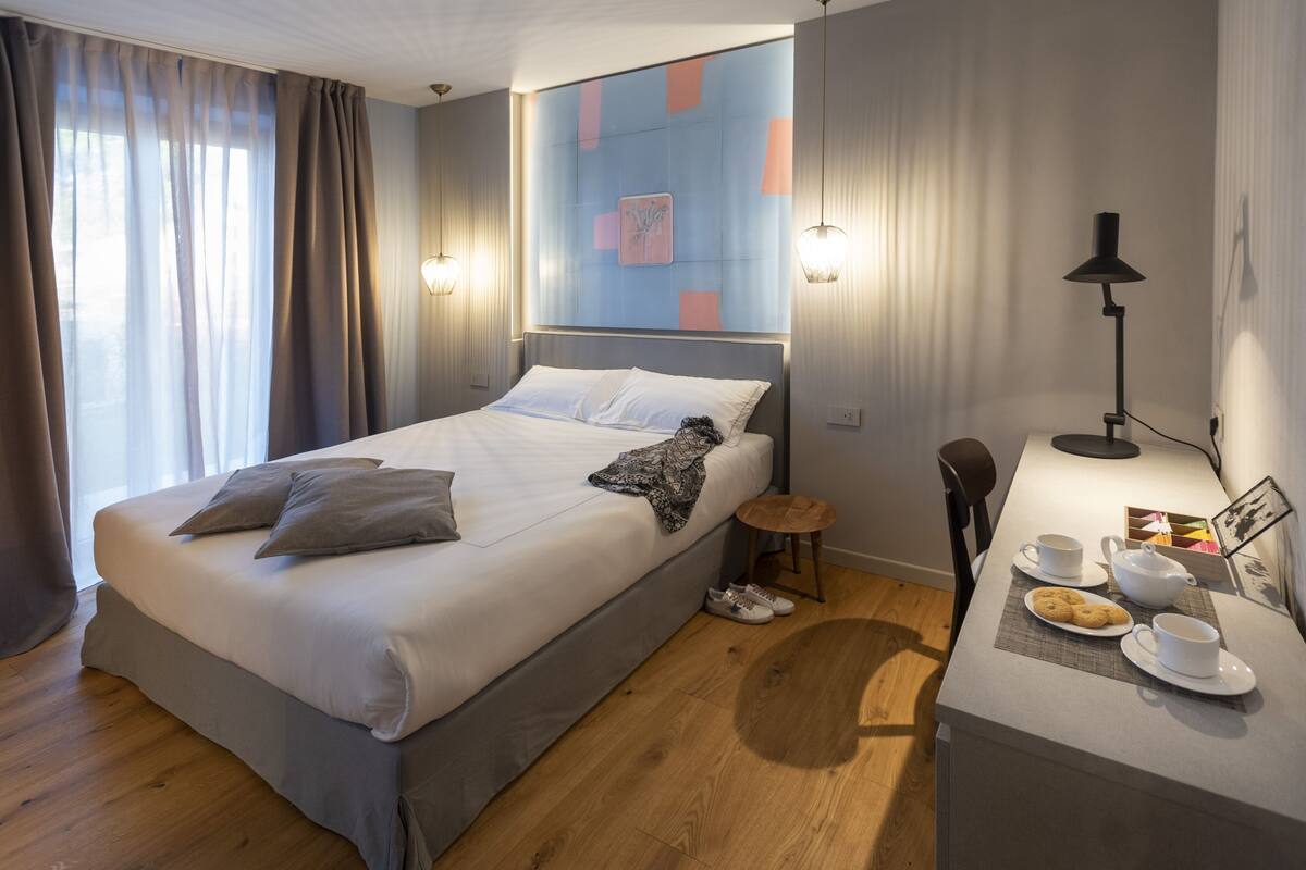 Una habitación de hotel moderna con una cama grande, una mesita de noche y un escritorio con una silla.
