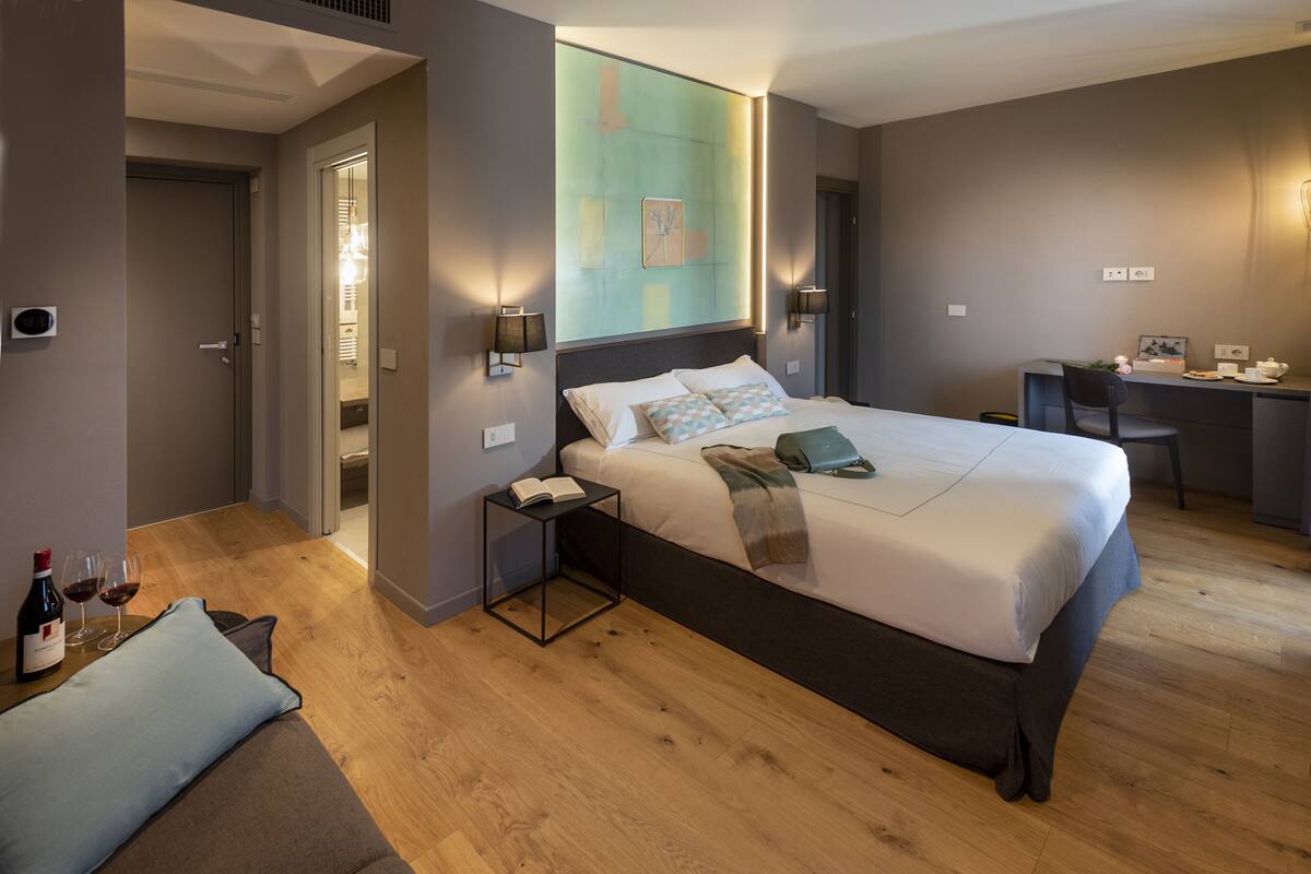 Una habitación de hotel moderna con una cama grande, mesitas de noche, un escritorio y una silla.