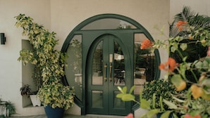 A green door with glass panels, potted plants, and a wooden deck. -  Ambiance Boutique Art Hotel Karachi (Karachi)