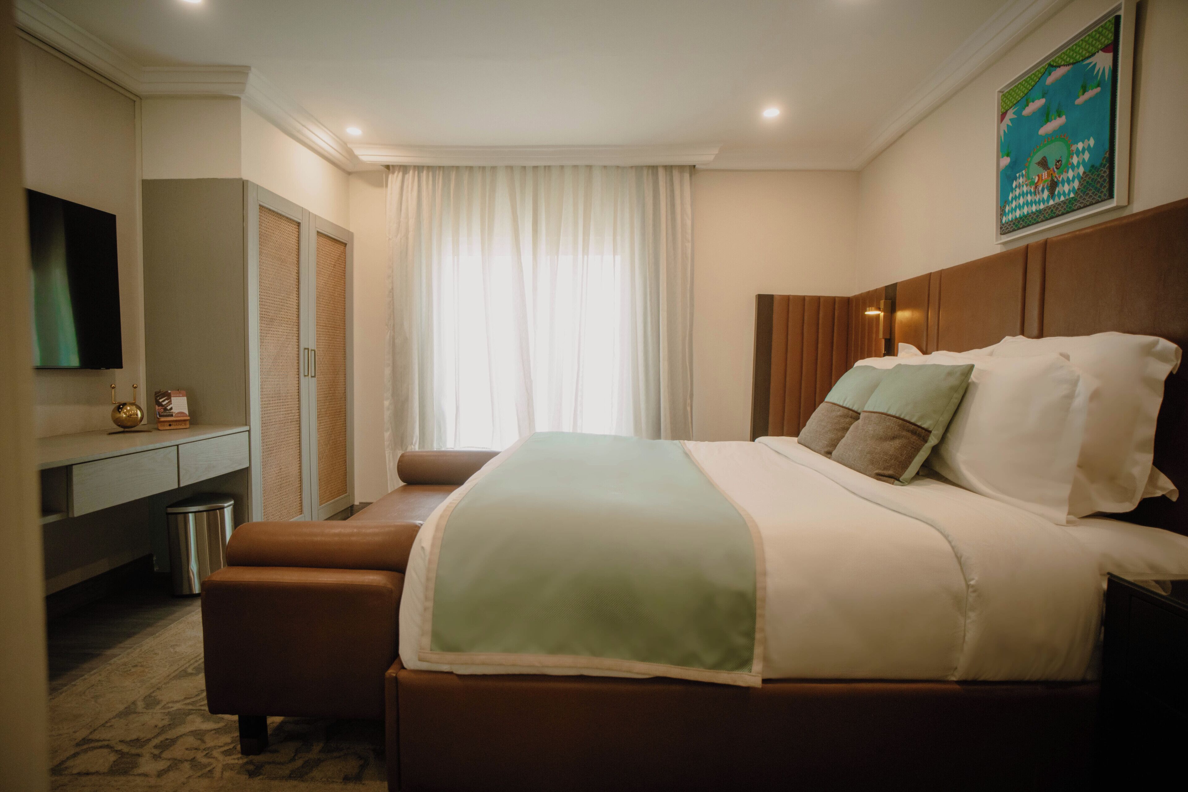 A hotel room with a bed, a television, a desk, and a window with curtains.