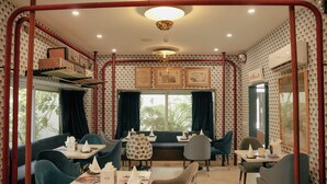 A dining area with tables and chairs, a bench, and a wall-mounted shelf with suitcases. -  Ambiance Boutique Art Hotel Karachi (Karachi)