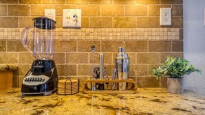 A kitchen with a granite countertop, a blender, a coffee maker, and a potted plant.