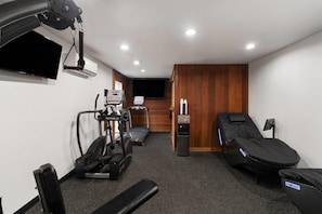 A gym with exercise equipment, a massage chair, and a television. - Ramada Bayside Inn & Suites Eureka (Eureka)
