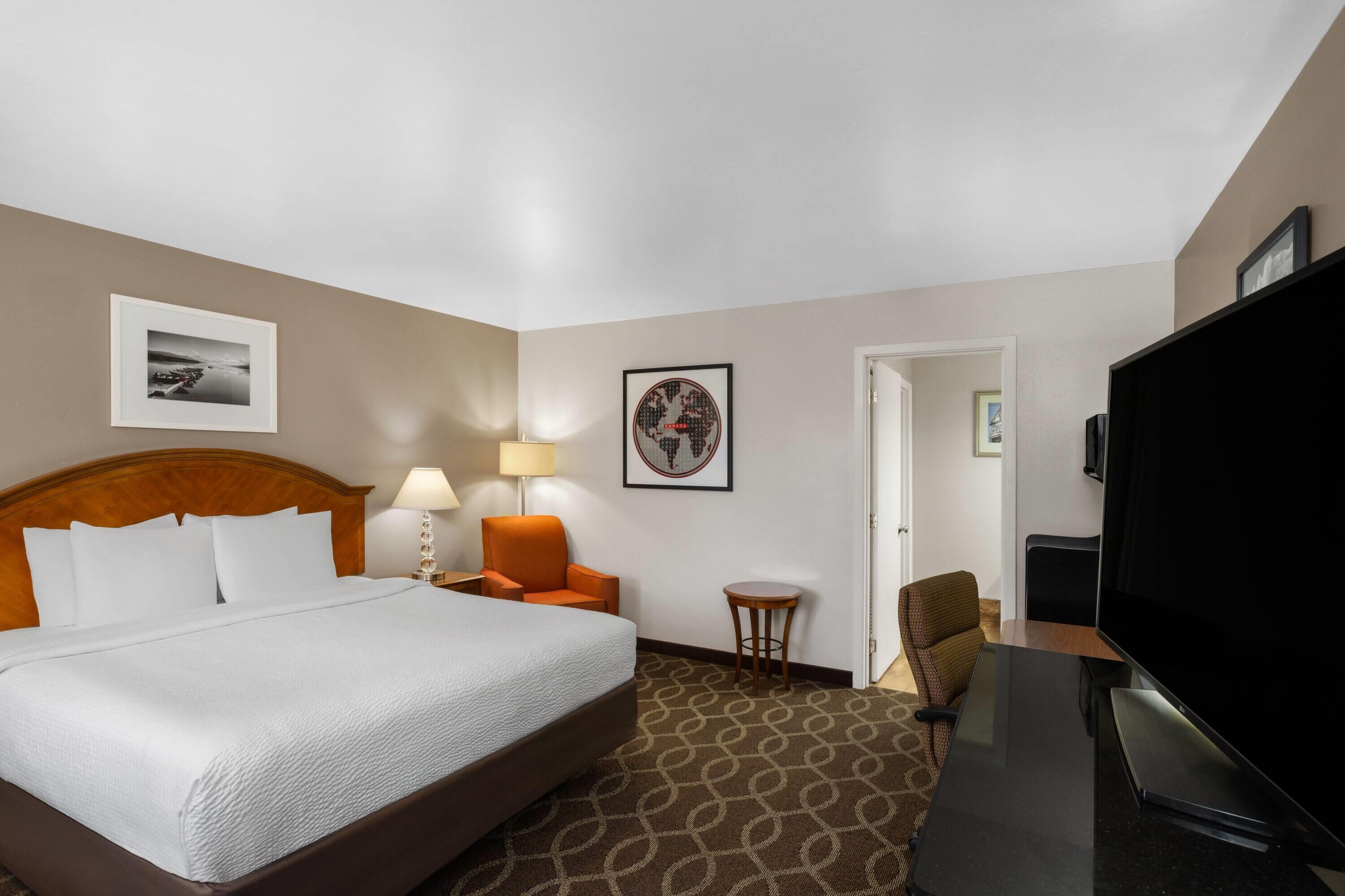 Ein Hotelzimmer mit Bett, Fernseher, Schreibtisch und zwei Stühlen.