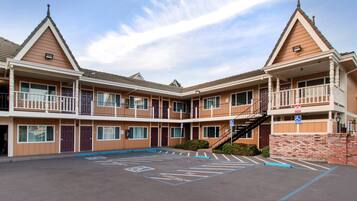 A multi-story motel with a central courtyard, a parking area marked with handicapped accessibility, and a staircase leading to the upper floors.