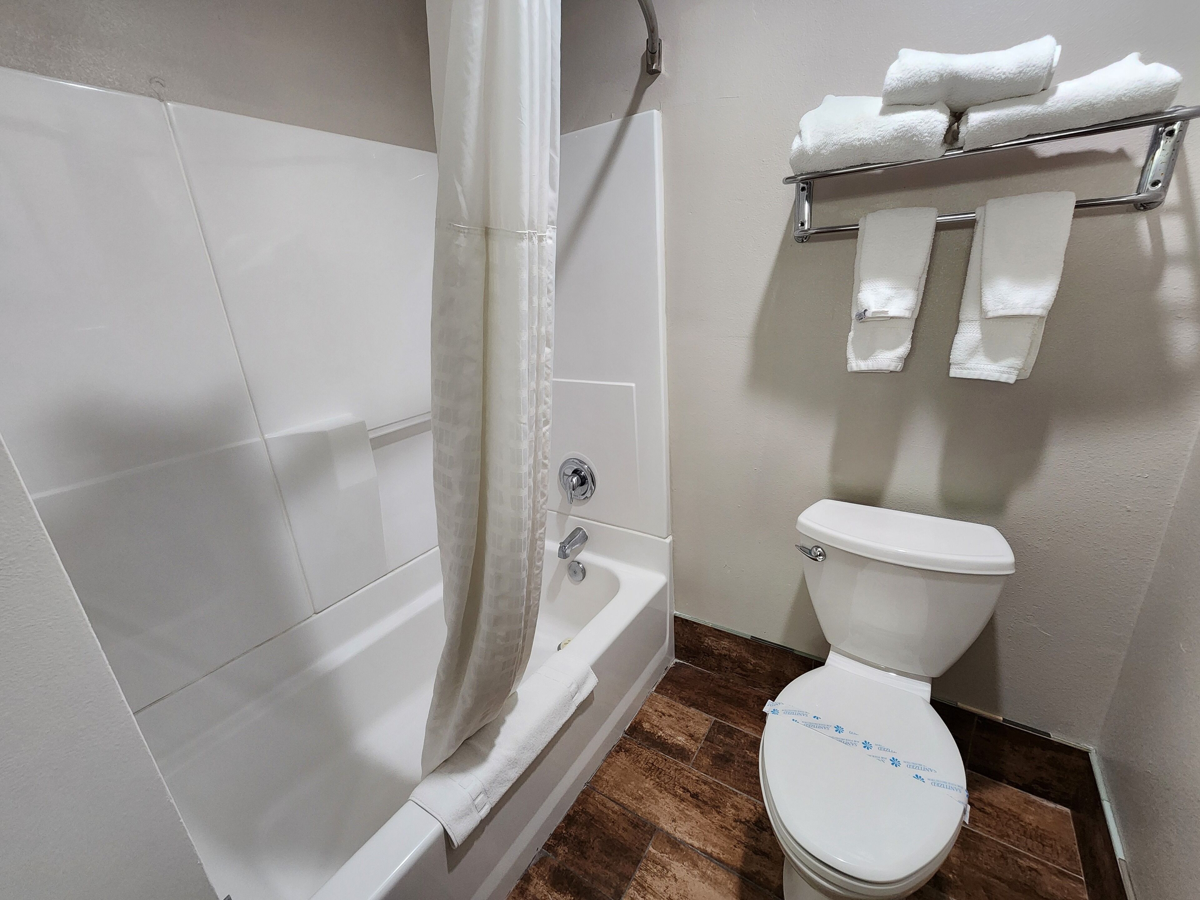 Un baño con bañera, inodoro y barra para toallas.