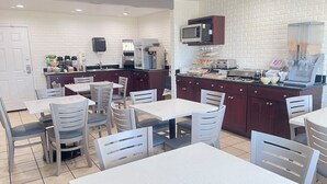 A clean, well-lit café with white and grey chairs, a coffee machine, a microwave, and a counter with various food items. - Ramada Bayside Inn & Suites Eureka (Eureka)