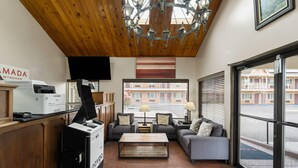 A hotel lobby with a wooden ceiling, a large window, a sofa, a coffee table, and a printer. - Ramada Bayside Inn & Suites Eureka (Eureka)