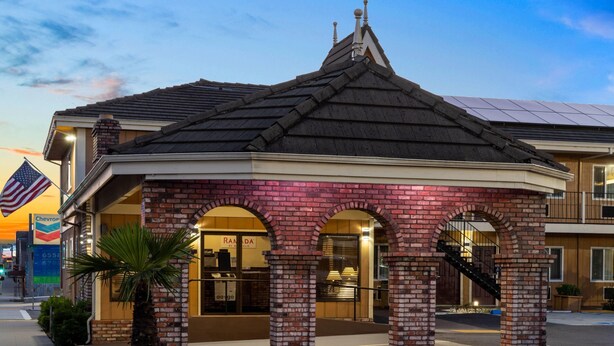 A brick building with a gabled roof, a Chevron gas station sign, and a restaurant named 'Randa.' - Ramada Bayside Inn & Suites Eureka (Eureka)