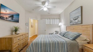 A bedroom with a bed, a ceiling fan, a nightstand, a dresser, and a painting on the wall. - 3 BR Condo w/ a Pool & Ocean Views Tahitian Condos (Wildwood Crest)