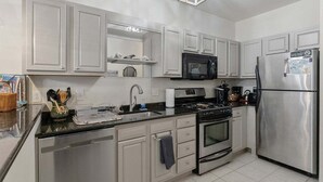 A modern kitchen with white cabinets, stainless steel appliances, and a black countertop. - 3 BR Condo w/ a Pool & Ocean Views Tahitian Condos (Wildwood Crest)