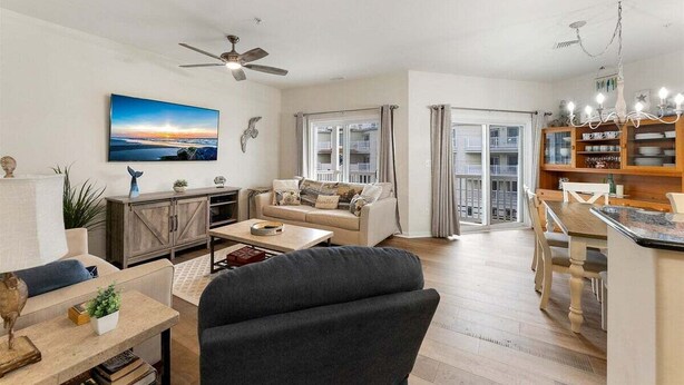 A spacious living room with a sofa, coffee table, and TV. There is a dining area with a table and chairs. - 3 BR Condo w/ a Pool & Ocean Views Tahitian Condos (Wildwood Crest)