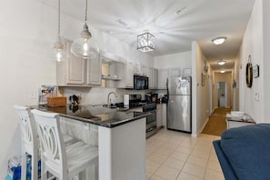 A modern kitchen with white cabinets, stainless steel appliances, and pendant lighting.