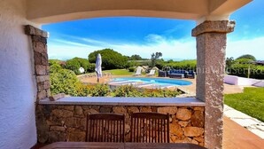 Un pati amb una paret de pedra, una piscina i vistes al paisatge.