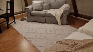 Ein gemütliches Schlafzimmer im Dachgeschoss mit einer Couch, einem Sessel und einer Lampe.