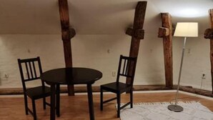 Ein Zimmer mit Holzboden, einem runden Tisch und vier Stühlen sowie einem weißen Teppich.