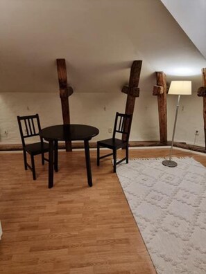 A room with a wooden floor, a round table with four chairs, and a white rug. - Cosy Apartment in Heart of Stockholm, Sweden (Stockholm)