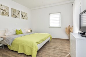 A bedroom with a bed, a nightstand, a TV, and wall art.