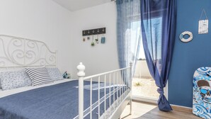 Une chambre à coucher comprenant un lit, des rideaux, une tête de lit, un porte-manteau fixé au mur et un objet décoratif.