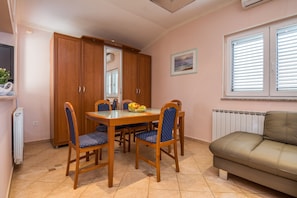A dining area with a wooden table and chairs, a sofa, and a radiator.