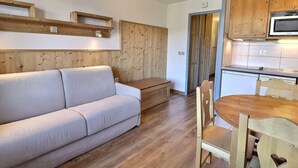 A cozy living area with a sofa, wooden floor, and a dining table with chairs. - Comfortable 2 Rooms, Ski-In/Ski-Out, Close to Shops (La Tania)