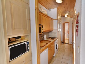 A kitchen with wooden cabinets, a microwave, a stove, and a washing machine.