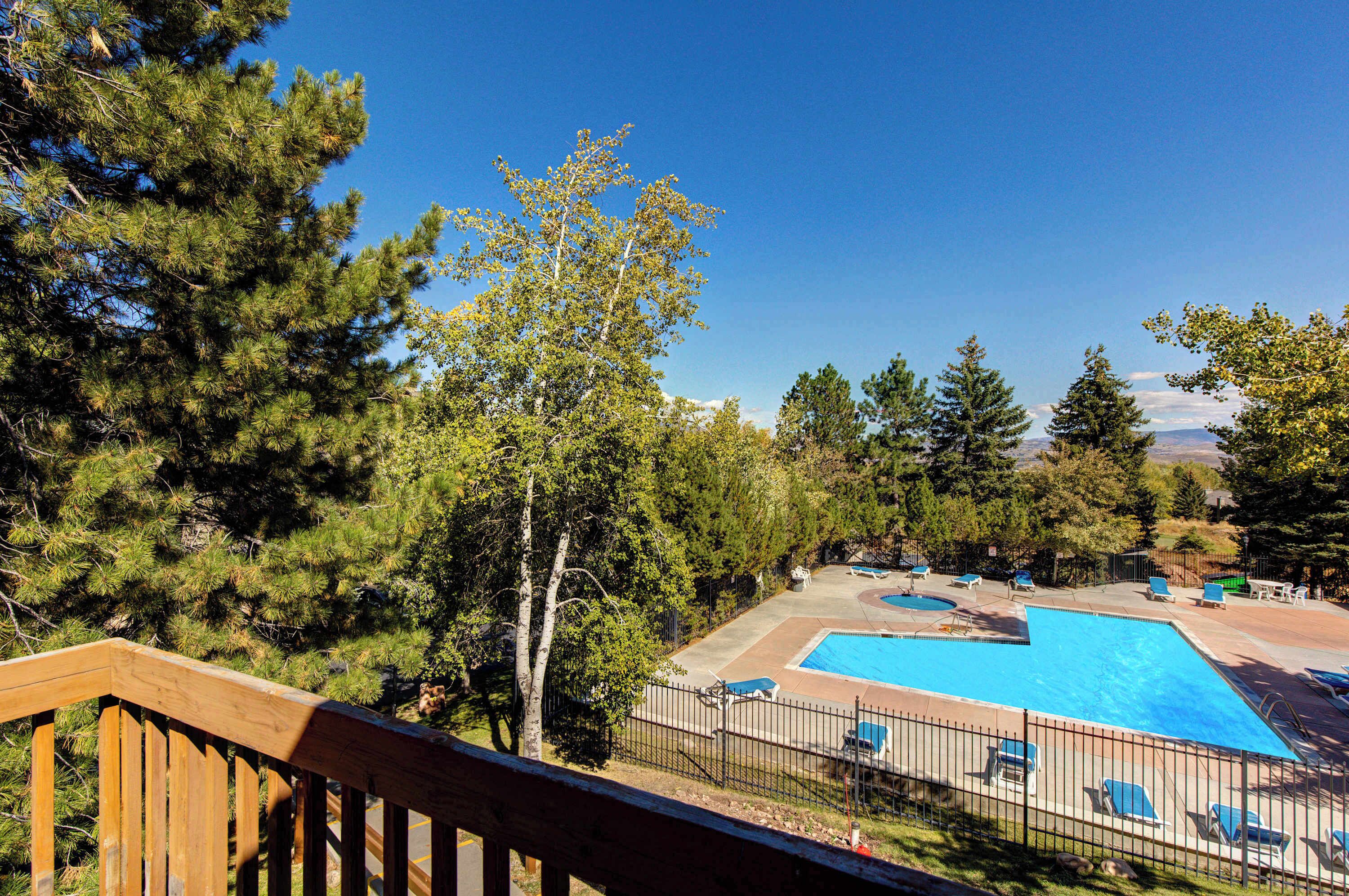 A pool with lounge chairs, surrounded by trees and a wooden deck.