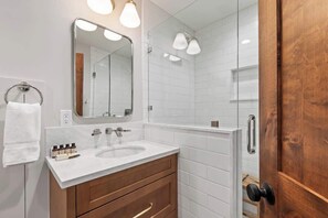 Un baño con lavamanos blanco, espejo y ducha.
