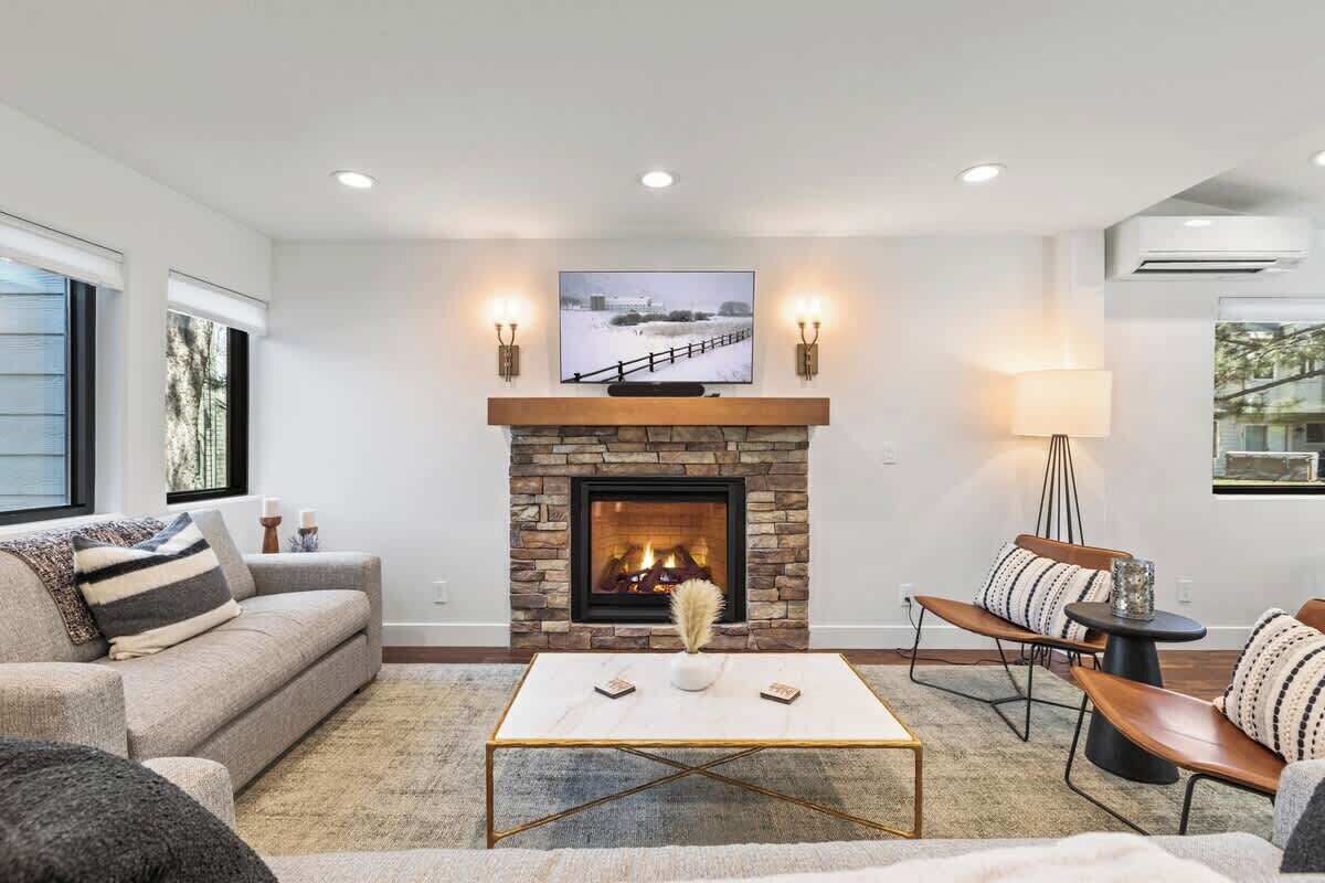 A living room with a stone fireplace, a television above it, and a sofa with striped cushions.