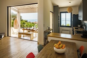 Una cocina moderna con un ventanal grande, un comedor con mesa de madera y vistas al exterior.