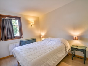 A bedroom with a bed, two bedside tables, a window with curtains, and a radiator. - Apartment Morzine 6 pers, near slopes, terrace, parking (Morzine)