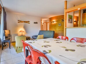 Een eetgedeelte met een tafel voor vier personen, een bank en een televisie op een standaard.