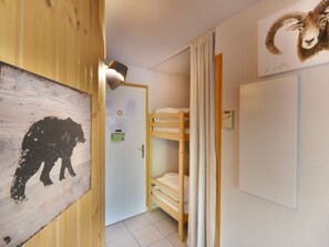 A room with a bunk bed, a wooden wall with a bear silhouette, a door with a no smoking sign, and a wall-mounted light fixture.