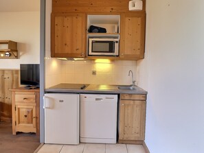 A compact kitchen with a microwave, dishwasher, and a small refrigerator.