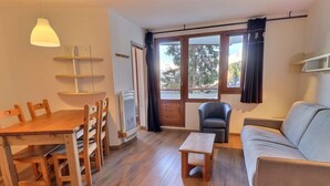 Una sala de estar con una mesa de comedor de madera, sillas, un sofá, una mesita de madera y un sillón gris.