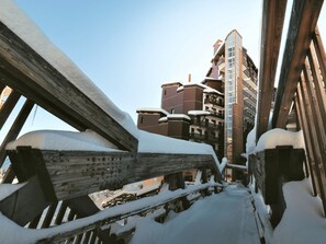 A snow-covered wooden structure with a view of a multi-story building in the background.