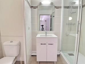 A bathroom with a toilet, a sink with a mirror, and a shower.