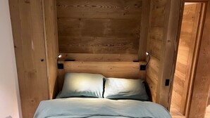 Een knus kamertje met houten wanden en een bed met lichtblauwe lakens.