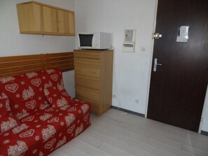 Cozy retreat with a single bed, microwave, and functional layout.