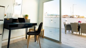A modern room with a desk, chair, and a view of the water and cityscape through large windows. - Duplex Penthouse with Jacuzzi in Historic Estepona, near Beach & Attractions (Estepona)
