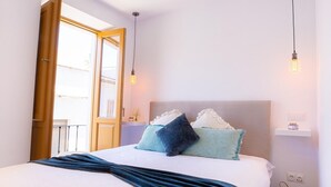 A bedroom with a bed, pillows, a bedside table, a lamp, a basket, and a door to an outdoor balcony. - Duplex Penthouse with Jacuzzi in Historic Estepona, near Beach & Attractions (Estepona)