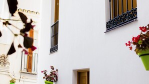 A white building with balconies, a door, and hanging flower pots. - Duplex Penthouse with Jacuzzi in Historic Estepona, near Beach & Attractions (Estepona)