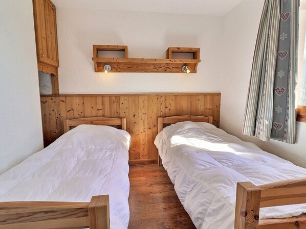 Una habitación con dos camas de madera, cabeceros de madera y una estantería con luces.