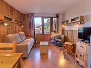 A wooden-furnished living room with a sofa, armchair, coffee table, TV, and wooden cabinets. - Comfortable 2-Room, Ski-in/Ski-out, Close to Shops (La Tania)