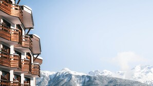 A multi-story building with balconies, set against a backdrop of snow-covered mountains. - Comfortable 2-Room, Ski-in/Ski-out, Close to Shops (La Tania)