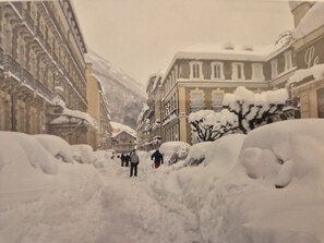 Une rue enneigée, bordée de bâtiments des deux côtés.