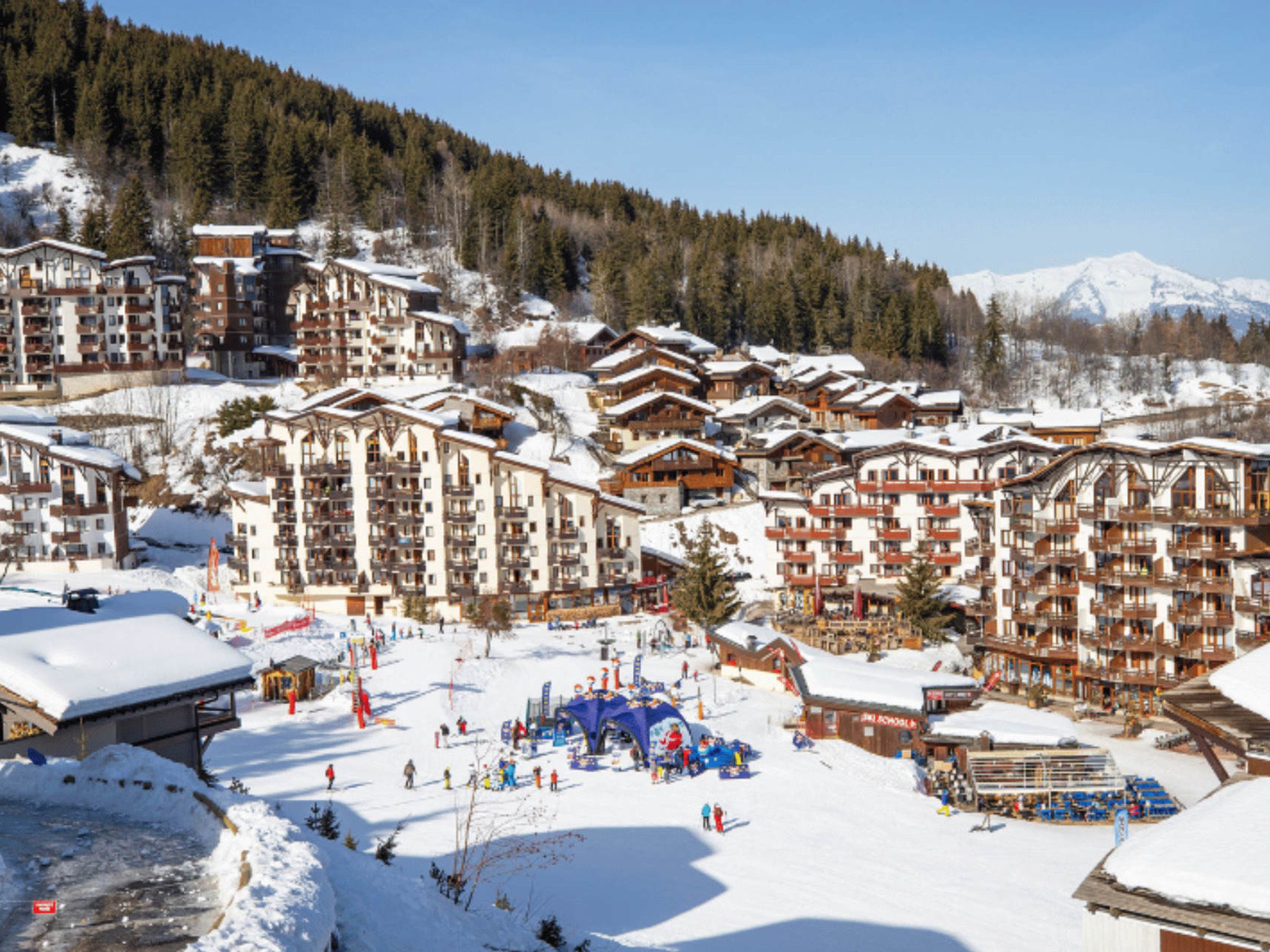 A ski resort with multiple chalet-style buildings, a ski lift, and a snowy landscape.