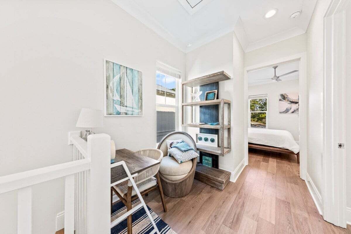 A compact room with a wooden floor, a dining table with chairs, a small seating area, a bed, and a ceiling fan.