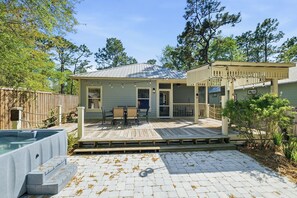 A house with a deck, outdoor seating, and a hot tub.